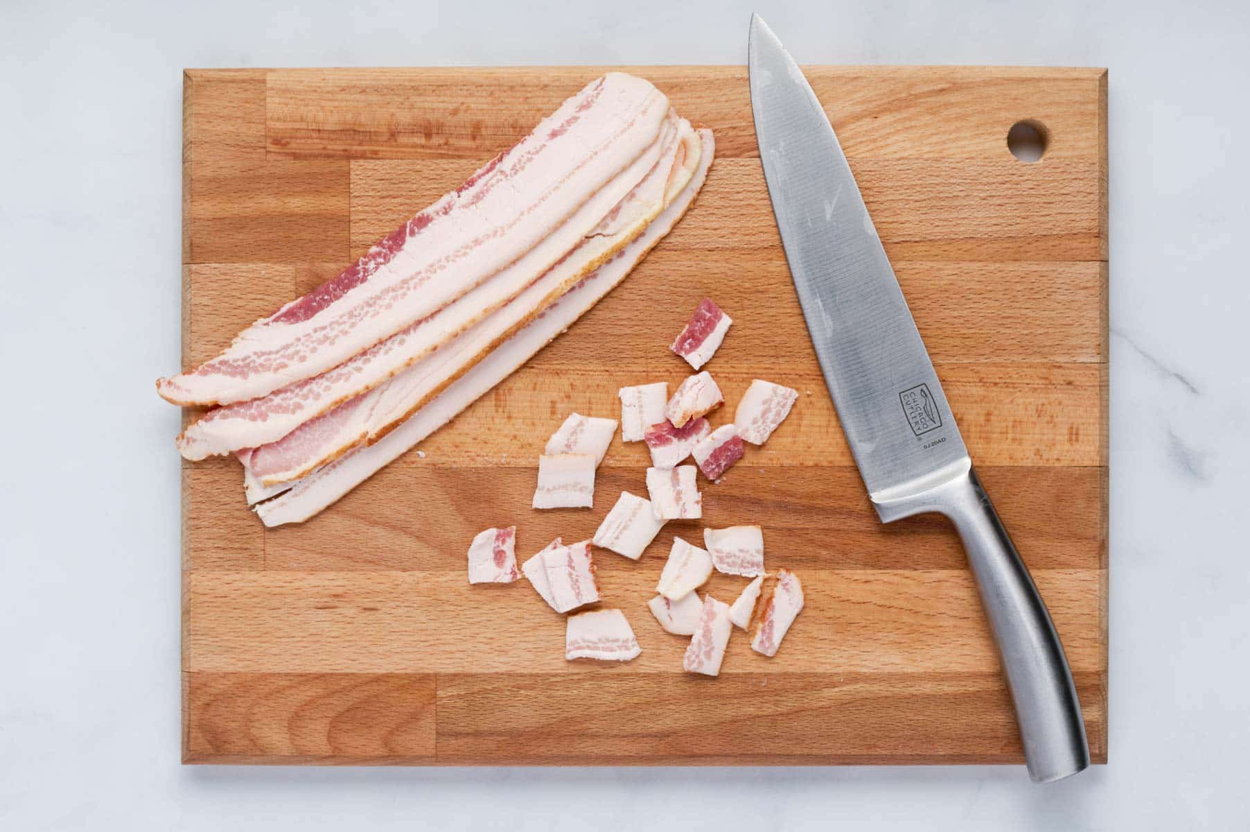 Bacon slices are chopped with a knife.