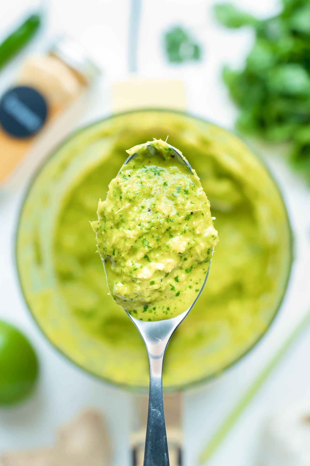 The best homemade Thai green curry paste is lifted up with a spoon.