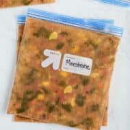 Multiple minestrone soups in a freezer-safe gallon-sized bags laying flat on the countertop frozen.
