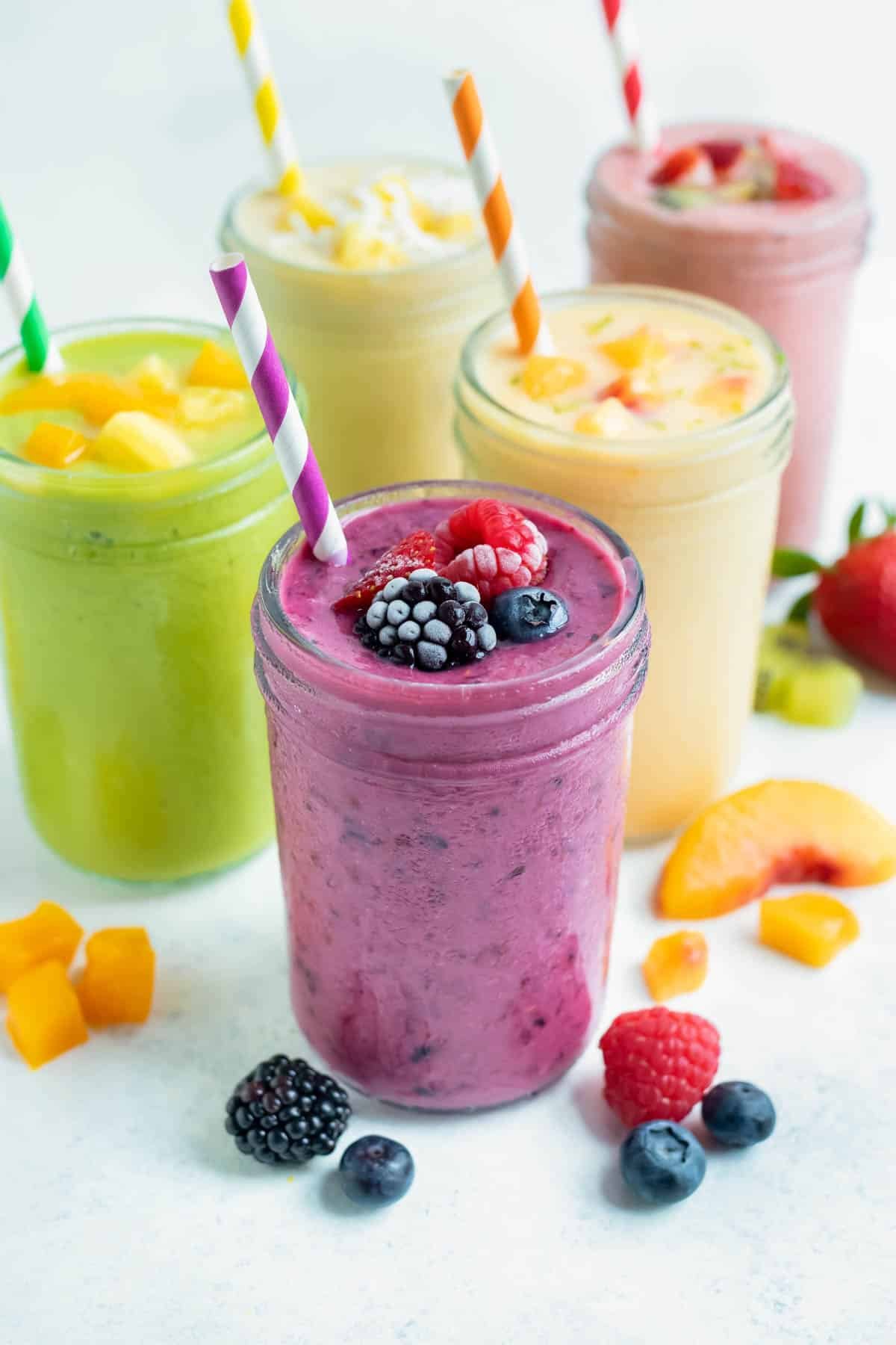 Five different frozen fruit smoothies are set on a counter.