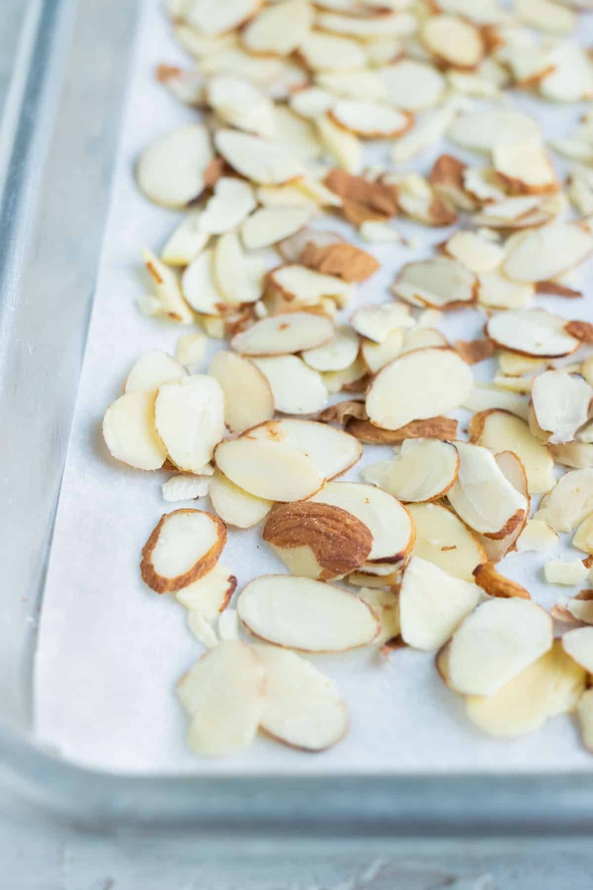 Sliced almonds are spread out on a sheet pan evenly before roasting.
