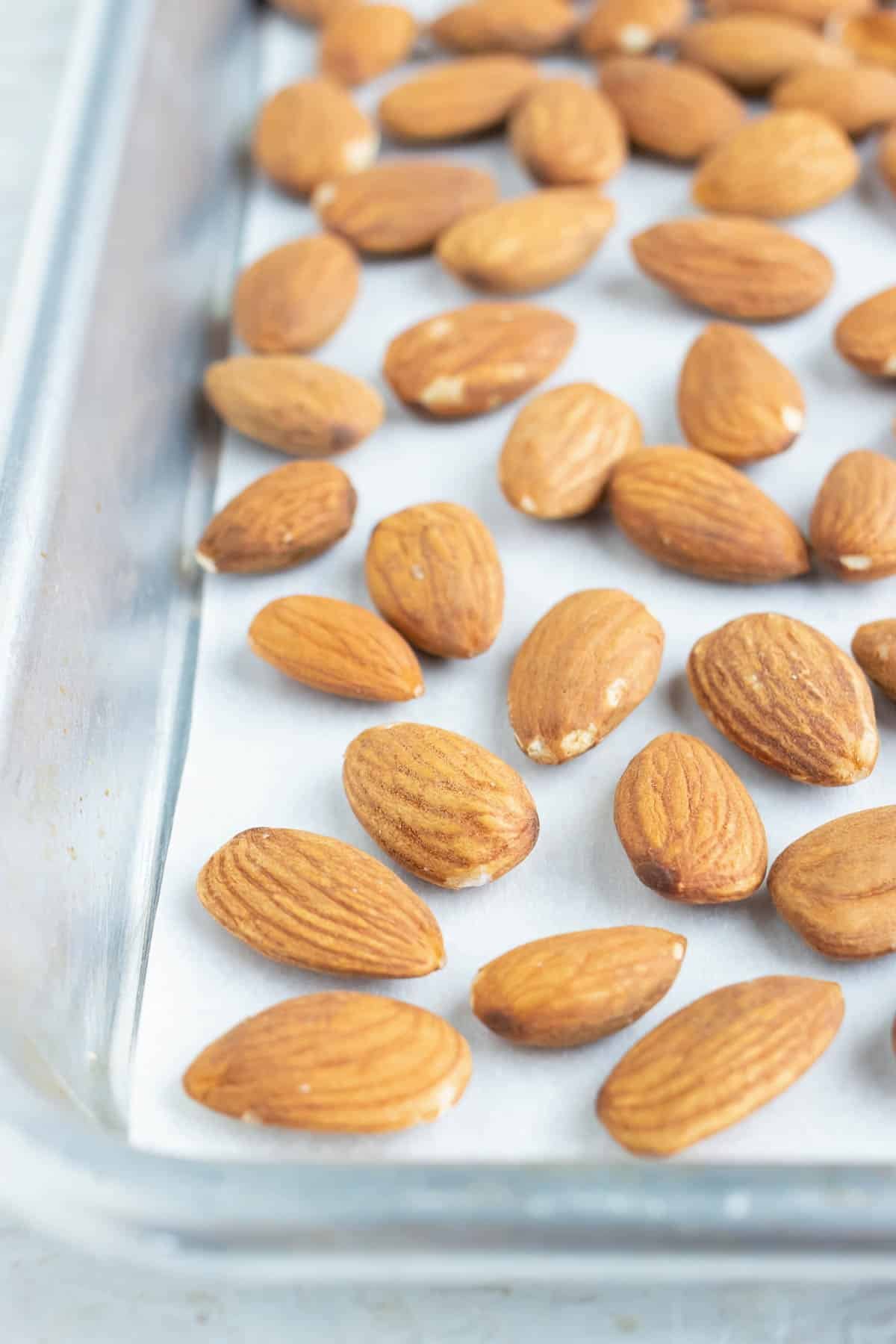 Almonds placed on a parchment paper lined baking sheet.