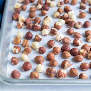 Raw hazelnuts are toasted in the oven on a baking sheet.