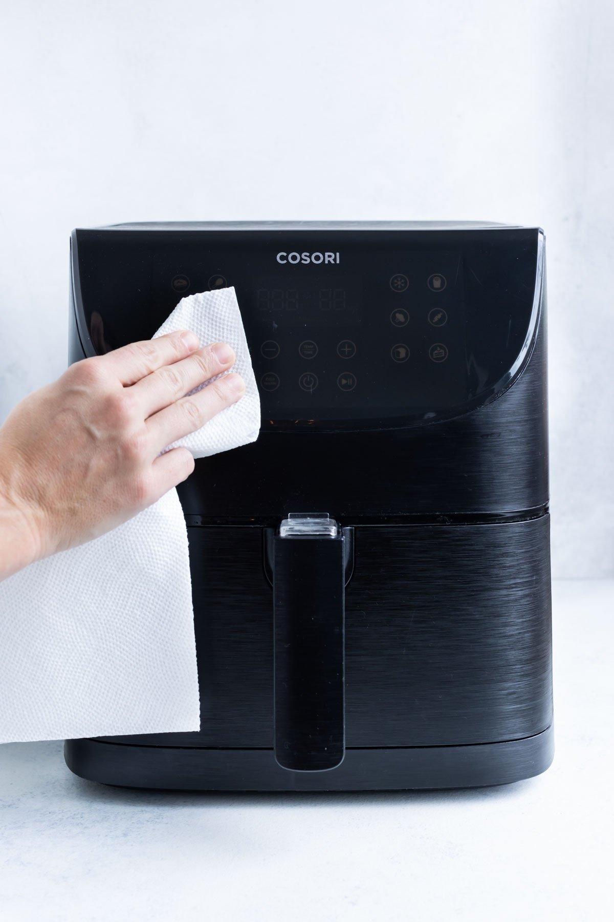 Wiping down the exterior of the air fryer with a damp paper towel.