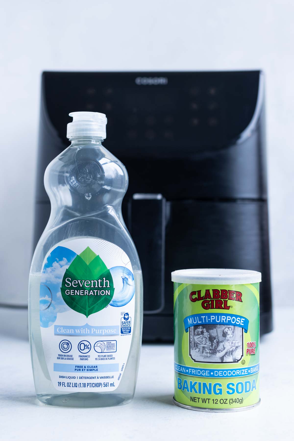 Colorless dish soap and baking soda place in front of a basket air fryer.