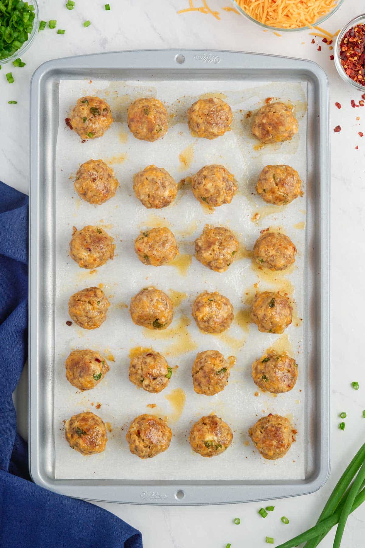 Golden brown sausage balls are baked in the oven.