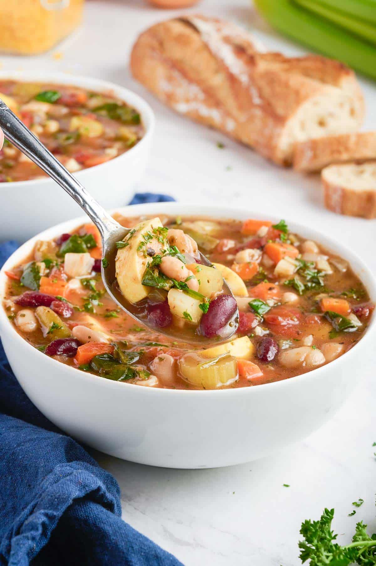 A spoonful of minestrone is enjoyed with fresh bread.