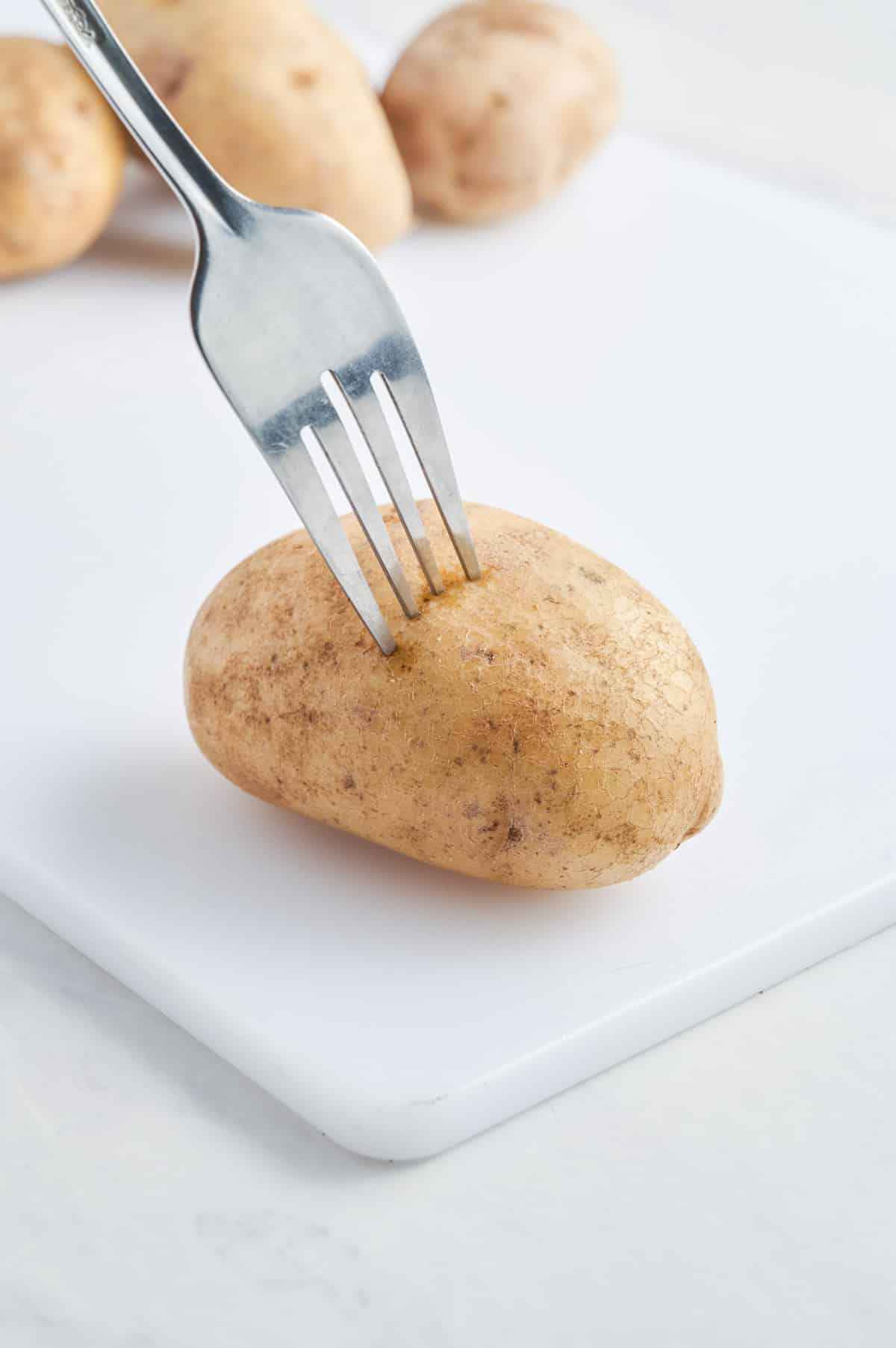 A fork pokes a potato.