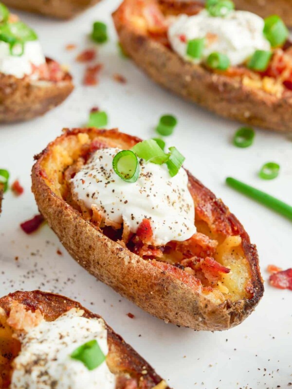 A close-up of baked potato skins with sour cream and chives.