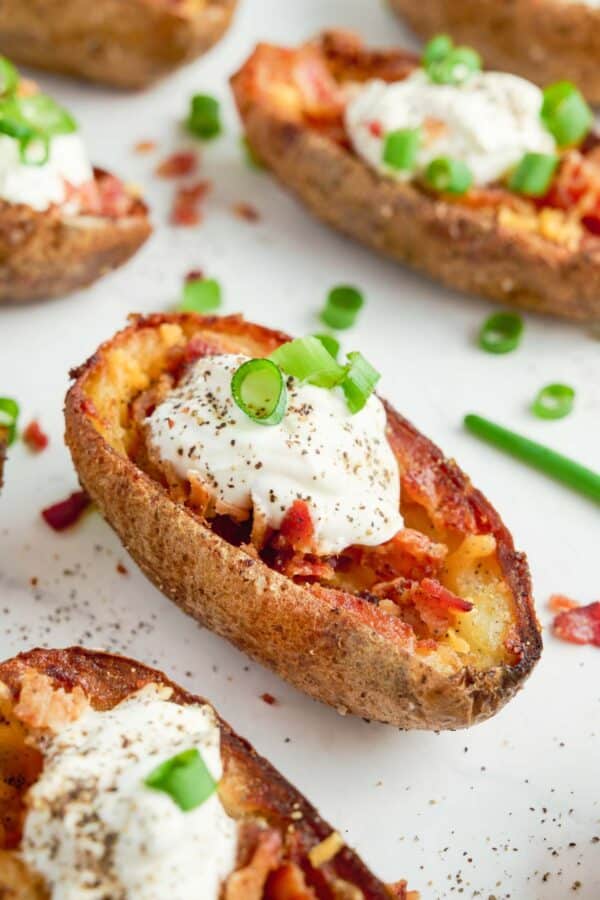 A close-up of baked potato skins with sour cream and chives.