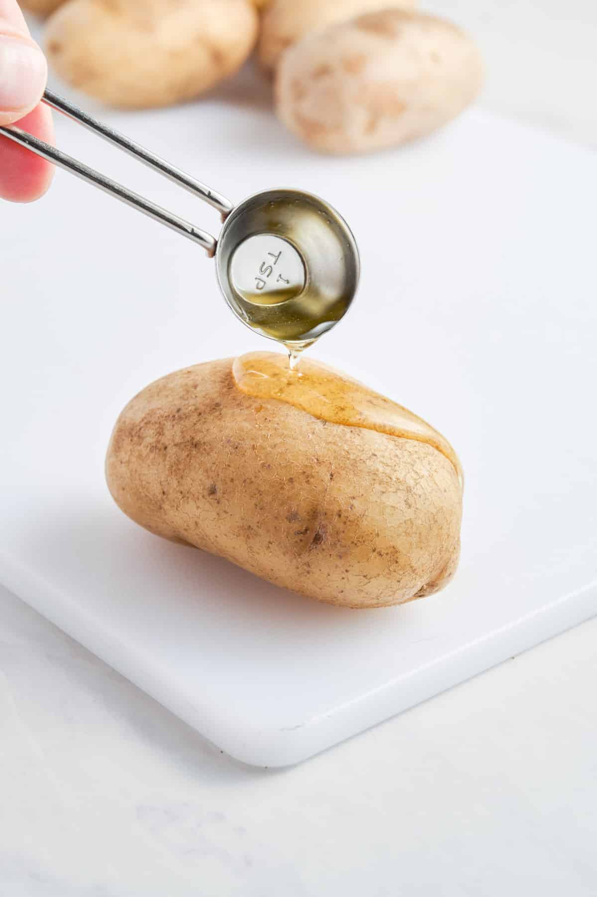 Oil is drizzled over a potato.