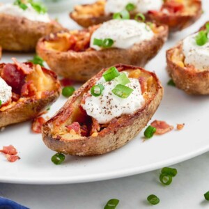 Potatoes are baked twice, topped with bacon and cheese, and served with sour cream and chives.
