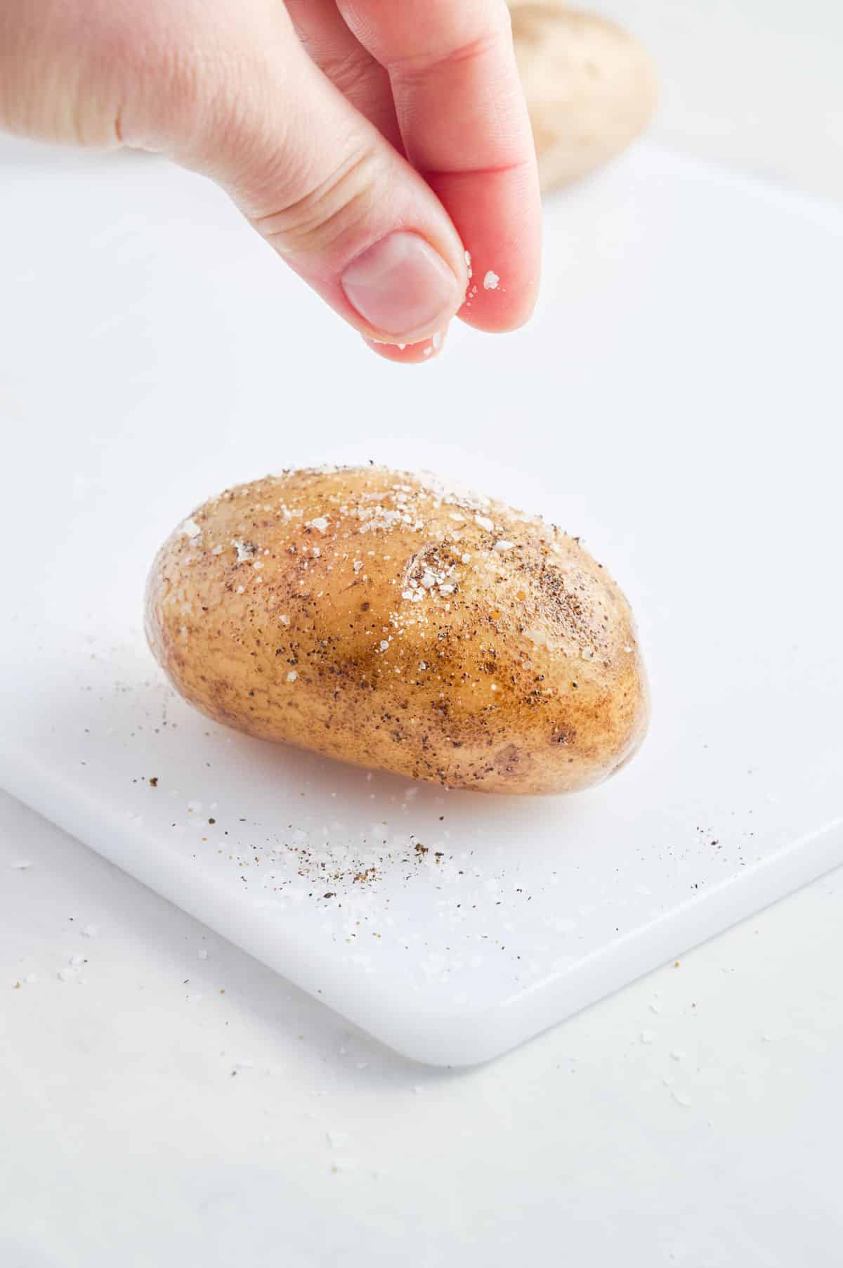 Salt is sprinkled on an oiled potato.