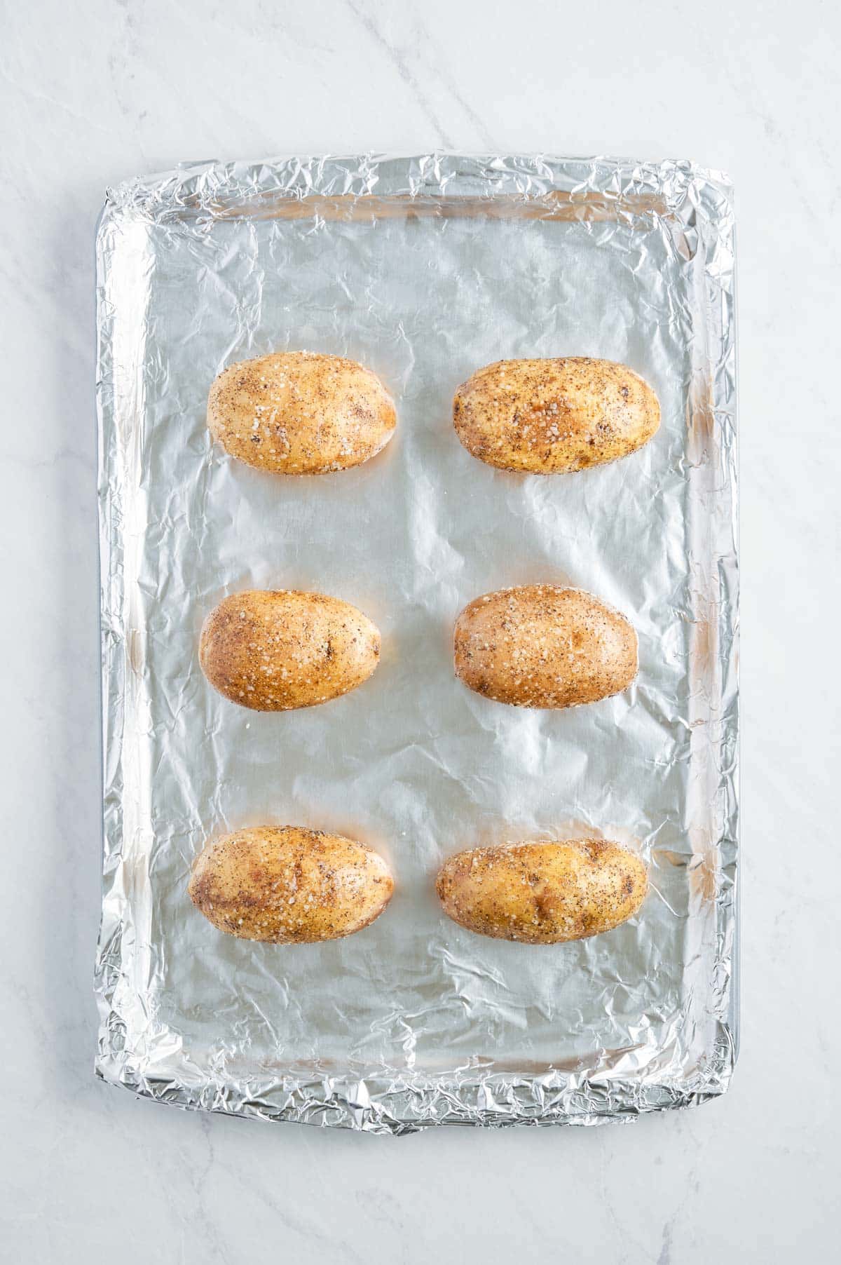 Potatoes are on a foil-lined baking sheet.