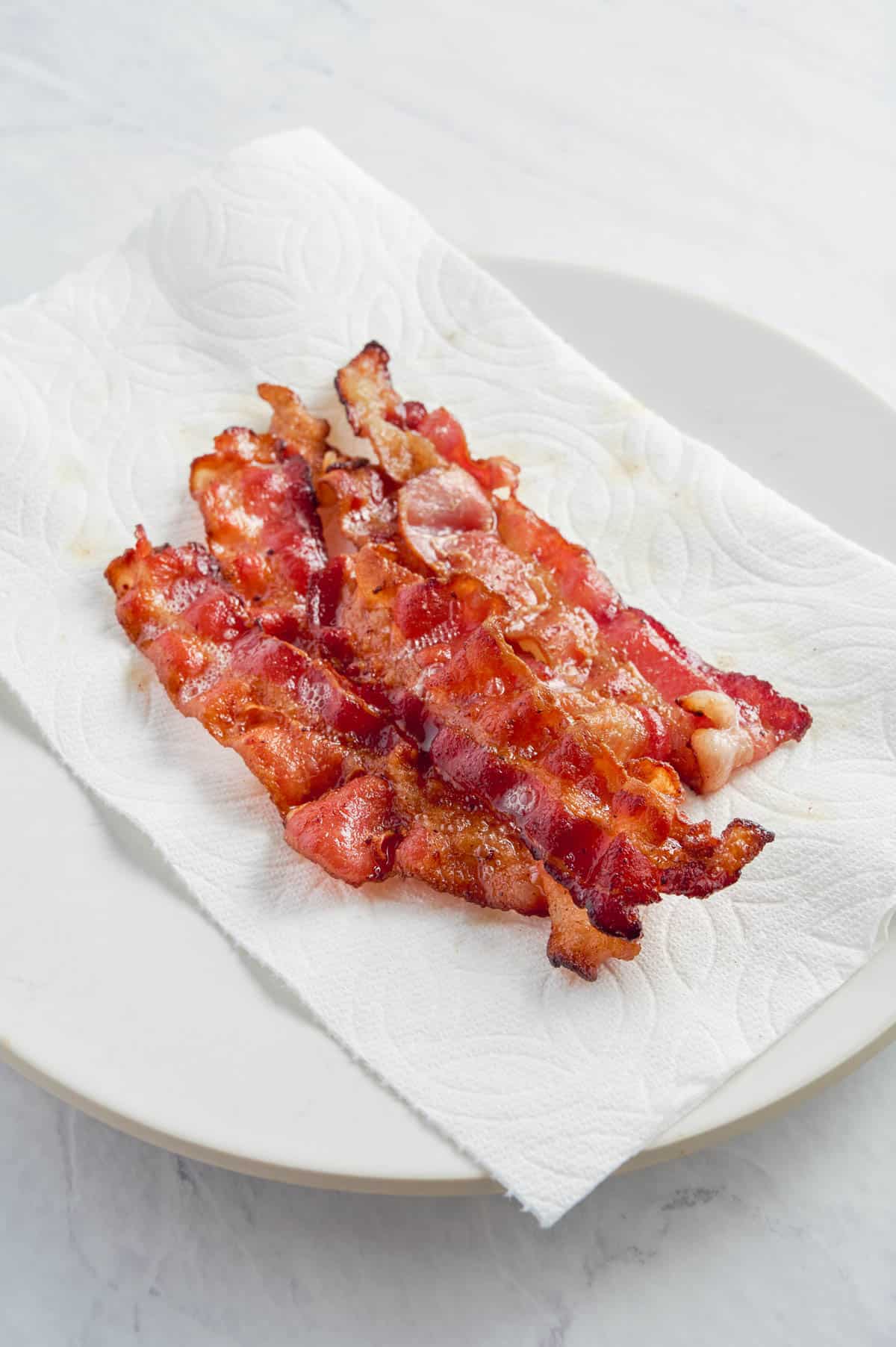 Bacon drains on a paper towel-lined plate.