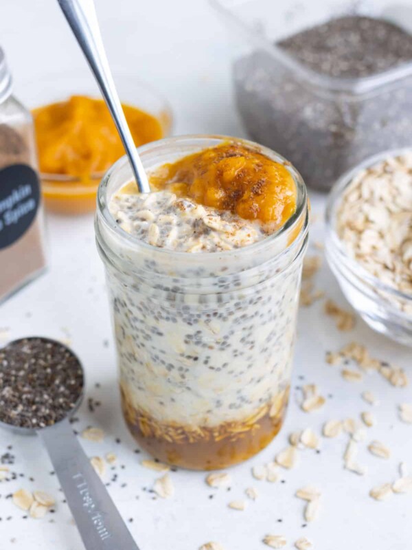 An easy pumpkin overnight oats recipe in a glass mason jar next to a blue napkin.