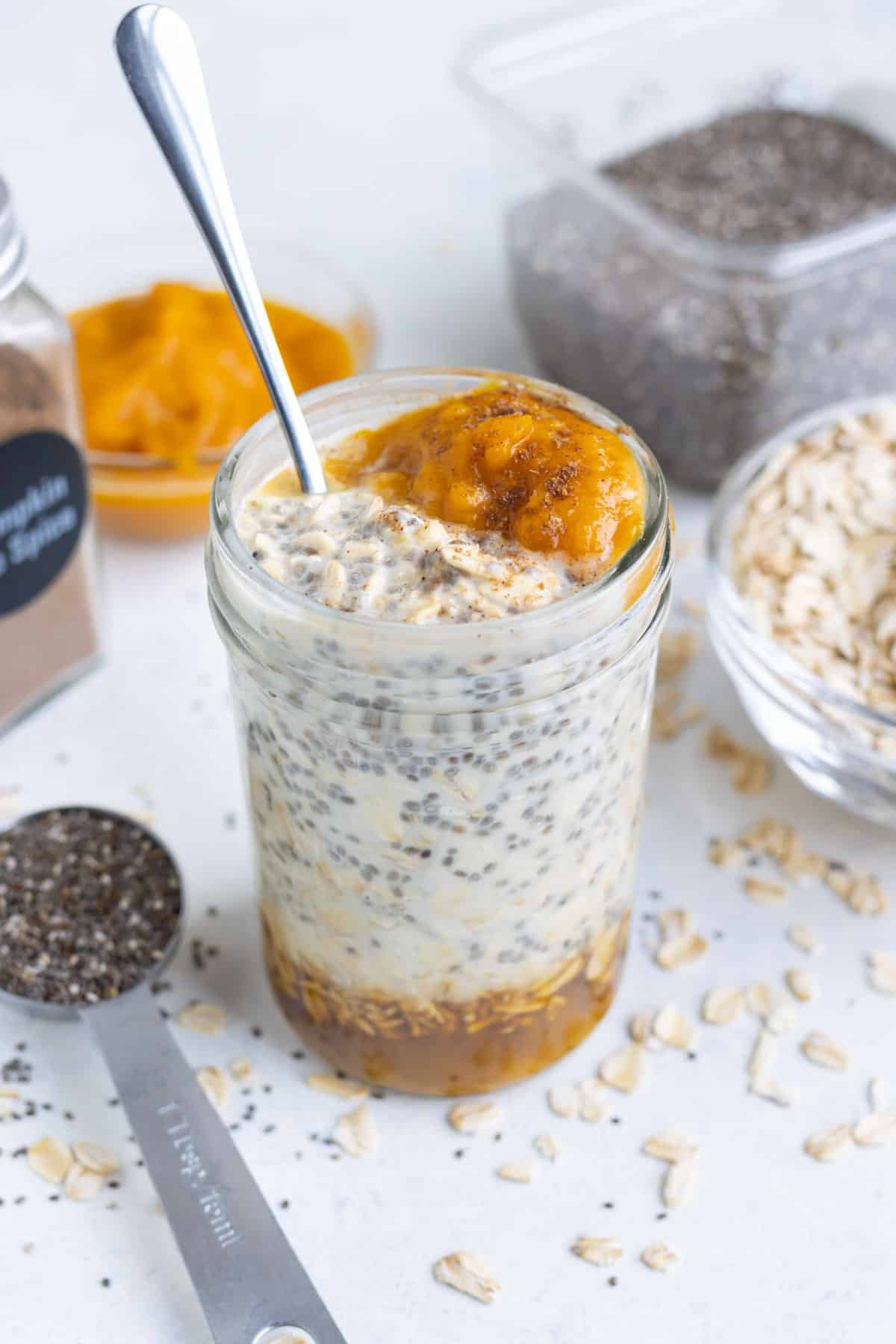 An easy pumpkin overnight oats recipe in a glass mason jar next to a blue napkin.