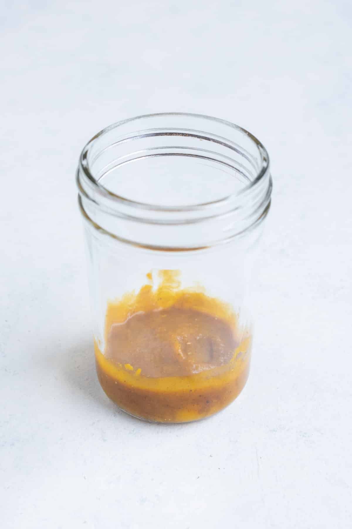 Pumpkin puree is added to the bottom of a jar.