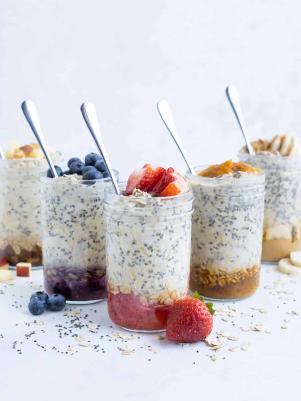 Multiple glass mason jars full of different flavors of overnight oats recipes.