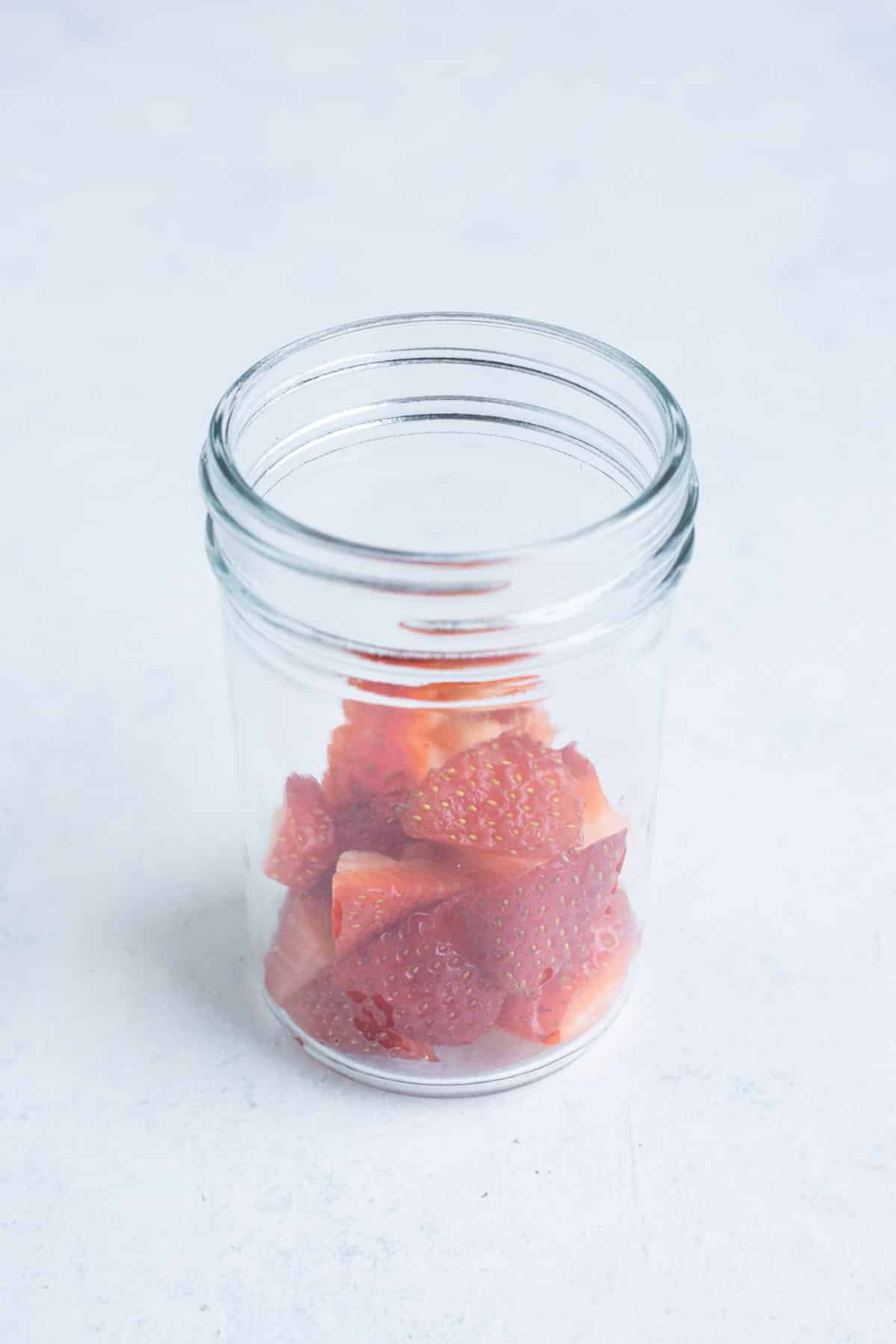 Strawberries are added to the jar.
