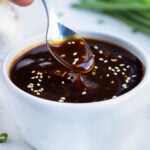 Healthy and gluten-free teriyaki sauce recipe is topped with sesame seeds and drizzled with a spoon.