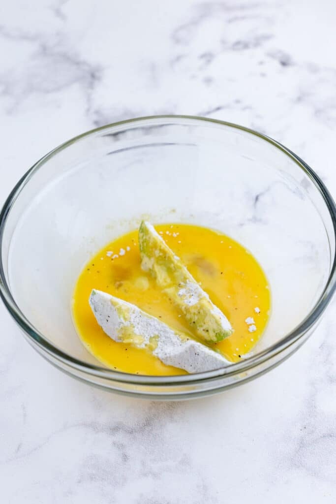 A floured avocado slice dredged in egg wash.