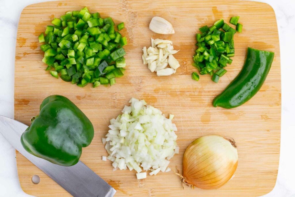 Diced onion, green bell pepper, jalapeño, and garlic on a cutting board for easy chicken korma