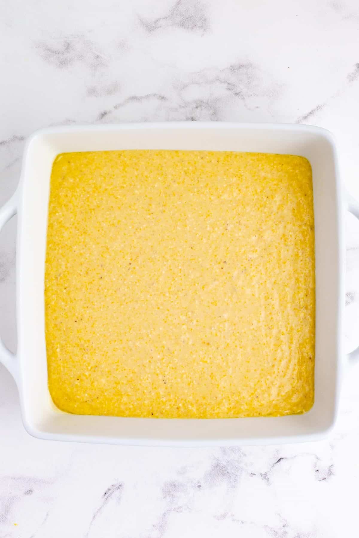 Cornbread batter is poured into a baking dish.