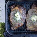 Garlic herb butter is dropped on top of steak.