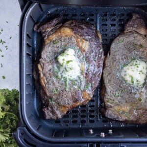 Garlic herb butter is dropped on top of steak.