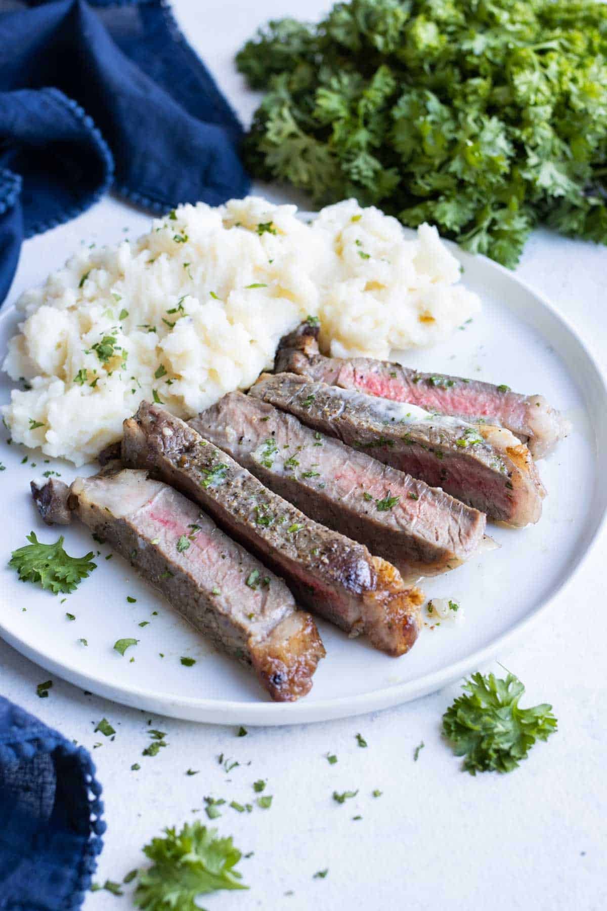 Sliced steak is served with mashed potatoes.
