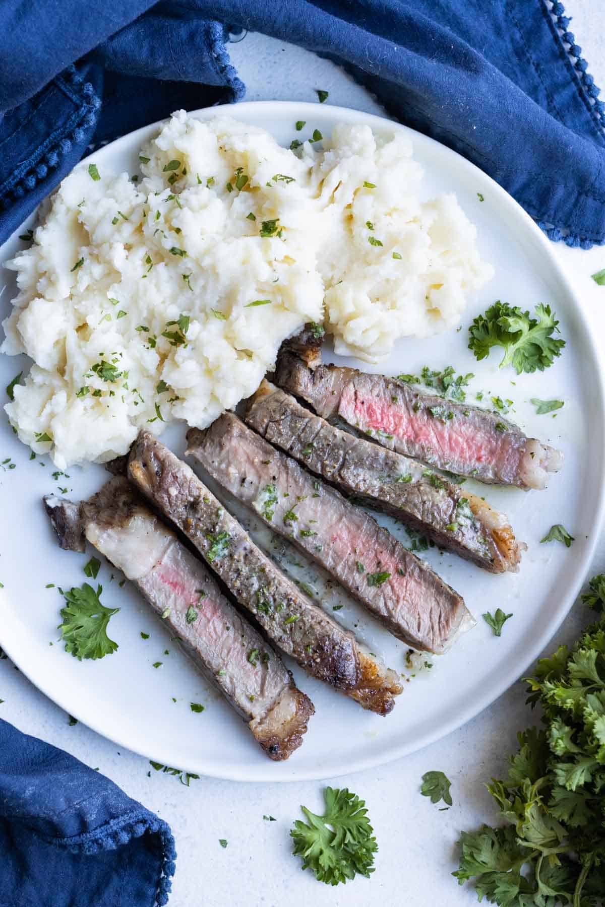 A white plate is full of steak and potatoes for a quick dinner.
