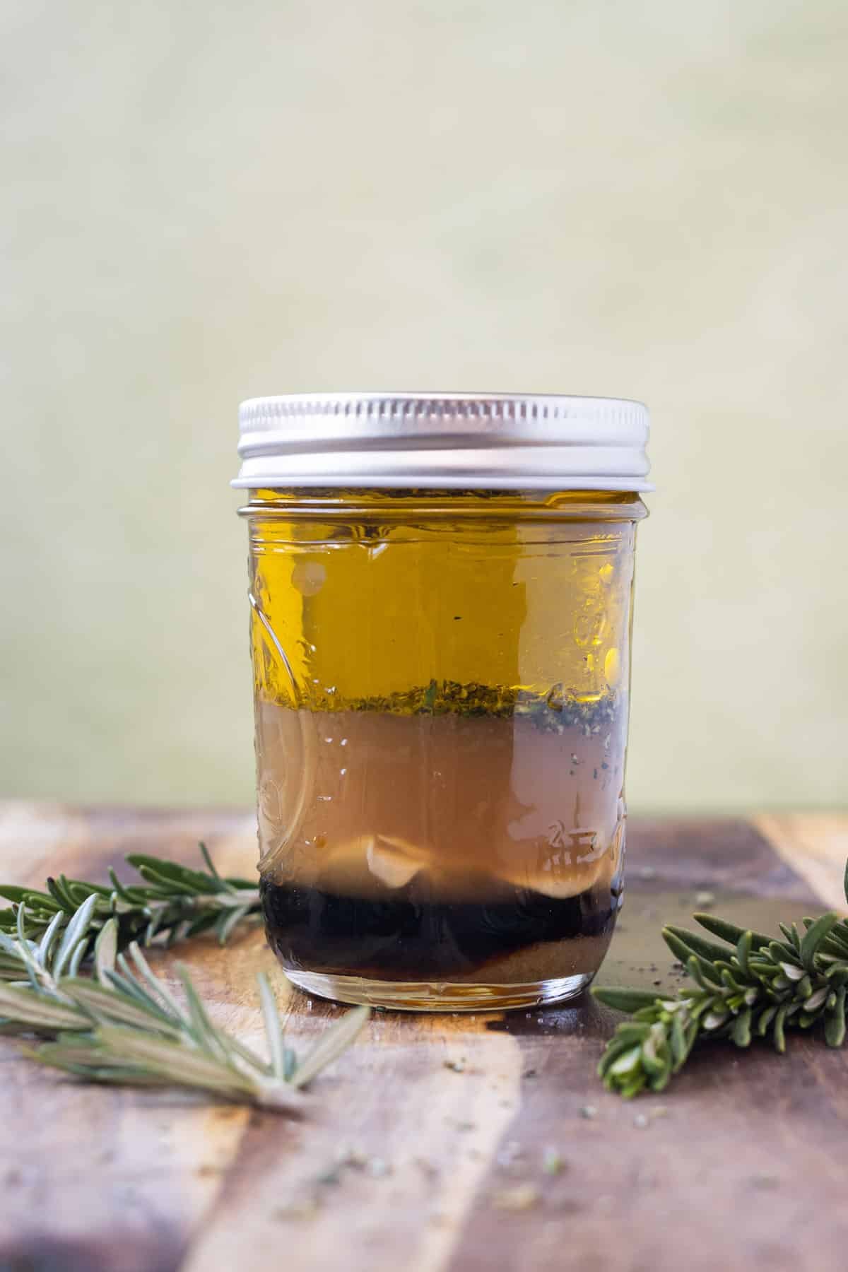 Ingredients for an apple cider vinaigrette are added to a mason jar.