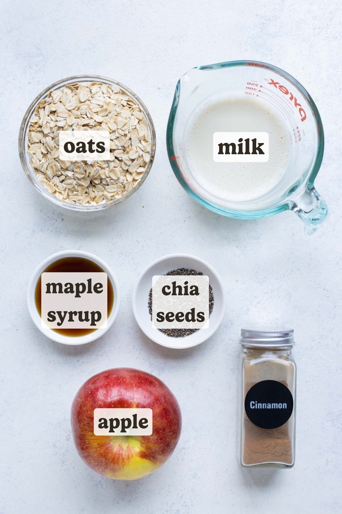 Oats, milk, syrup, chia seeds, apples, and spices are the ingredients for this overnight oats recipe.