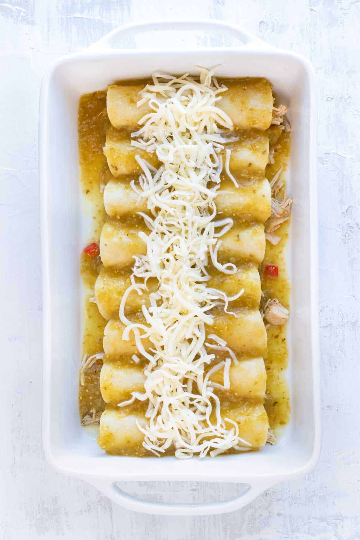 Enchiladas are covered with sauce and cheese before baking.