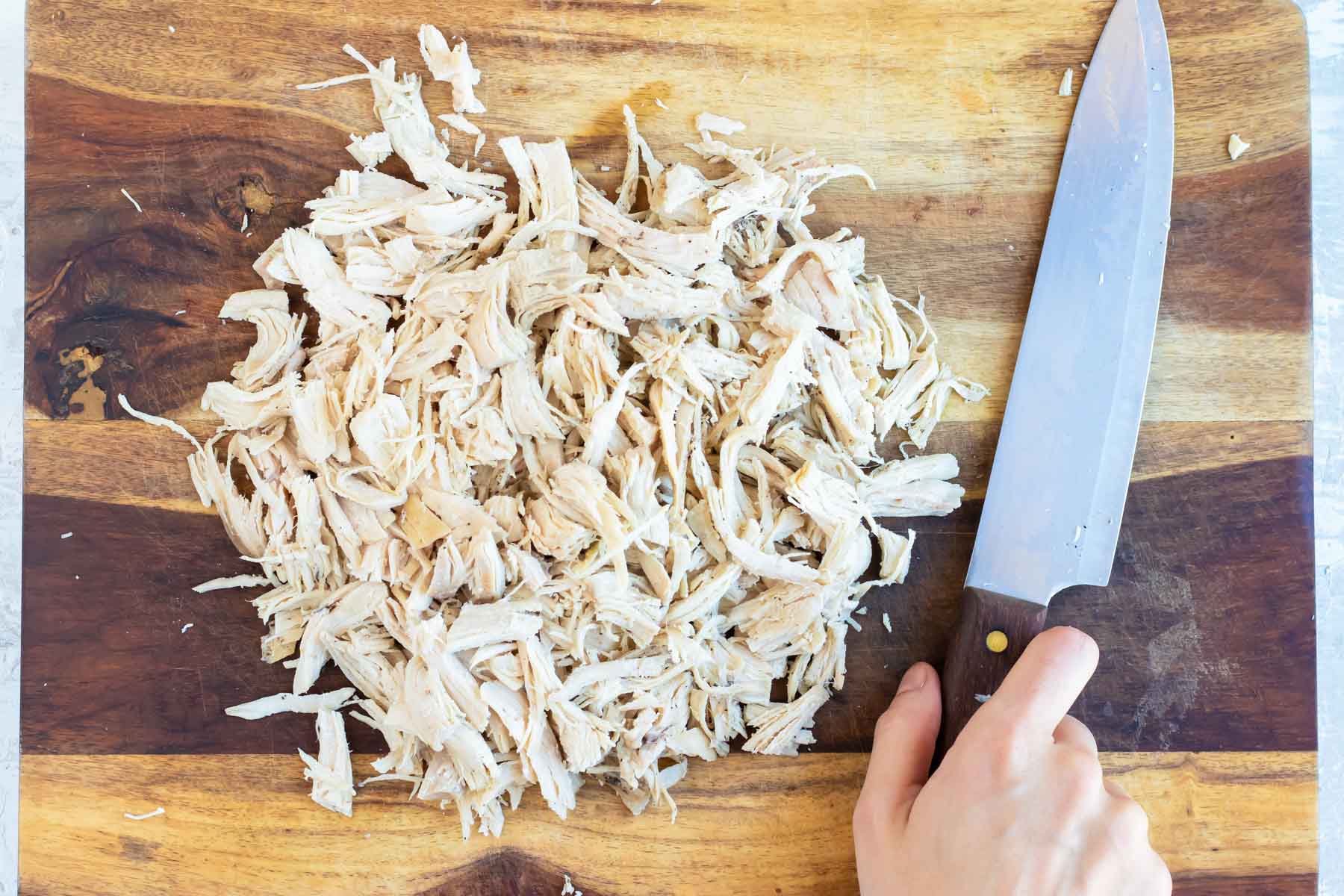 Chicken is chopped on a cutting board.