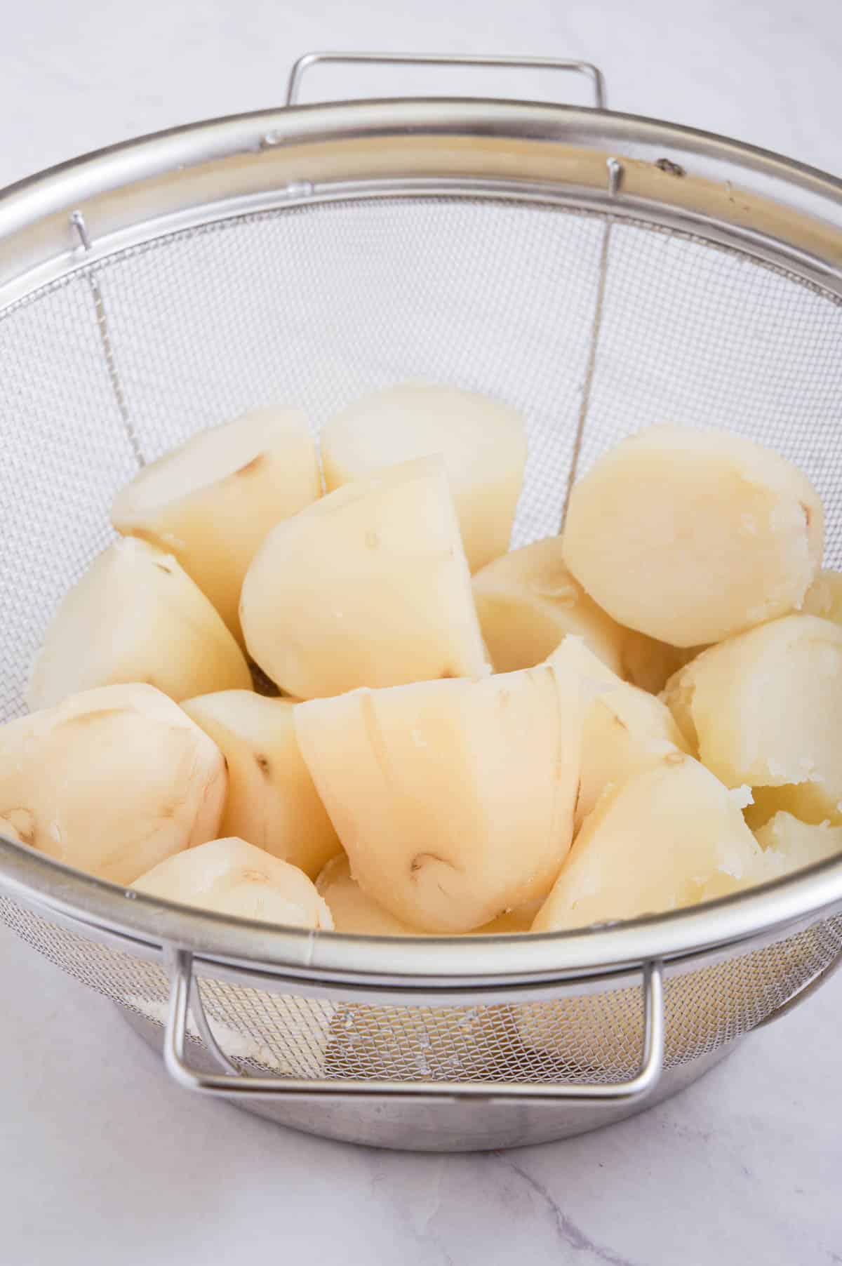 Cooked potatoes are drained in a colander.