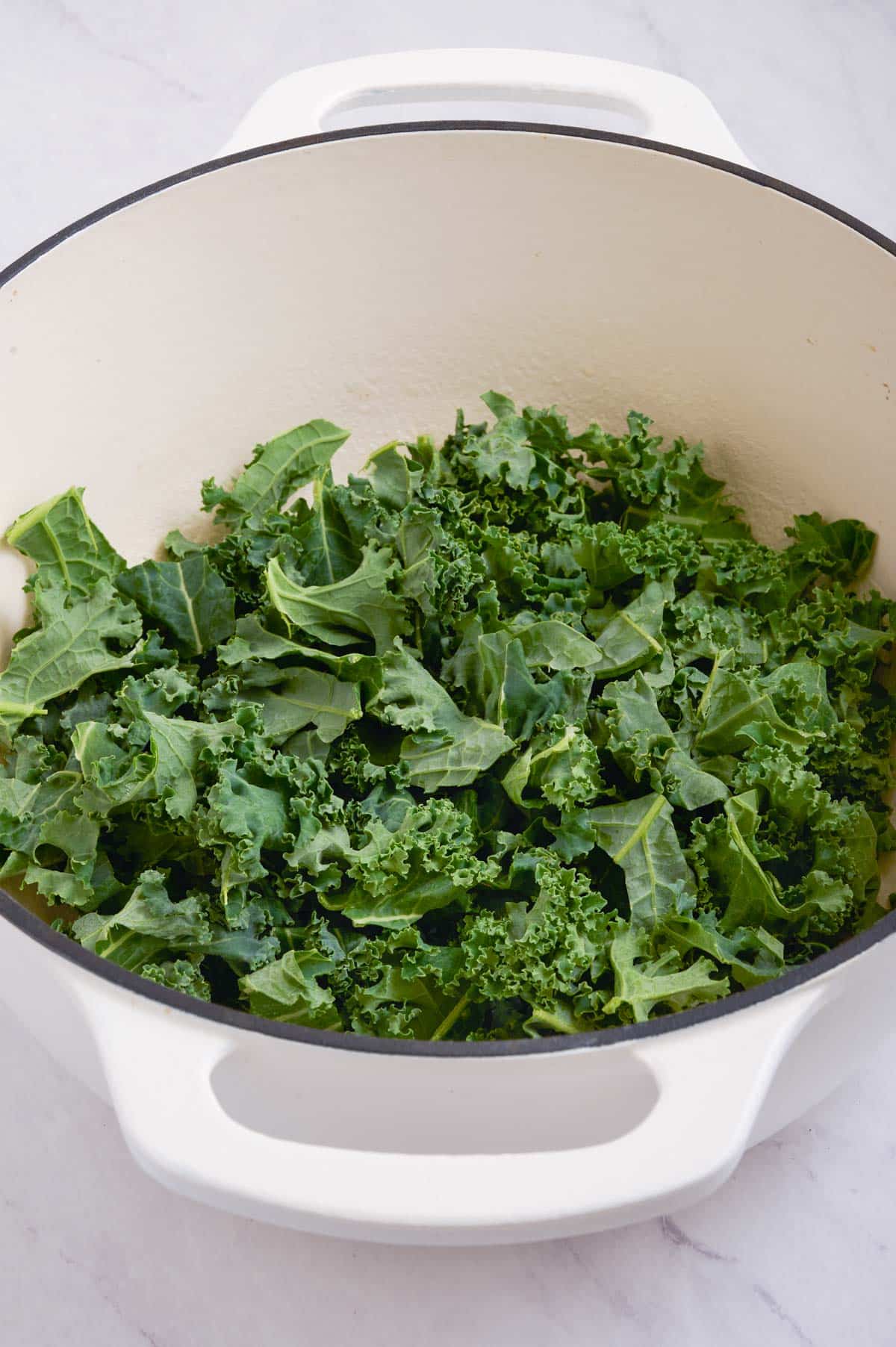 Kale is added to the butter in the pot.
