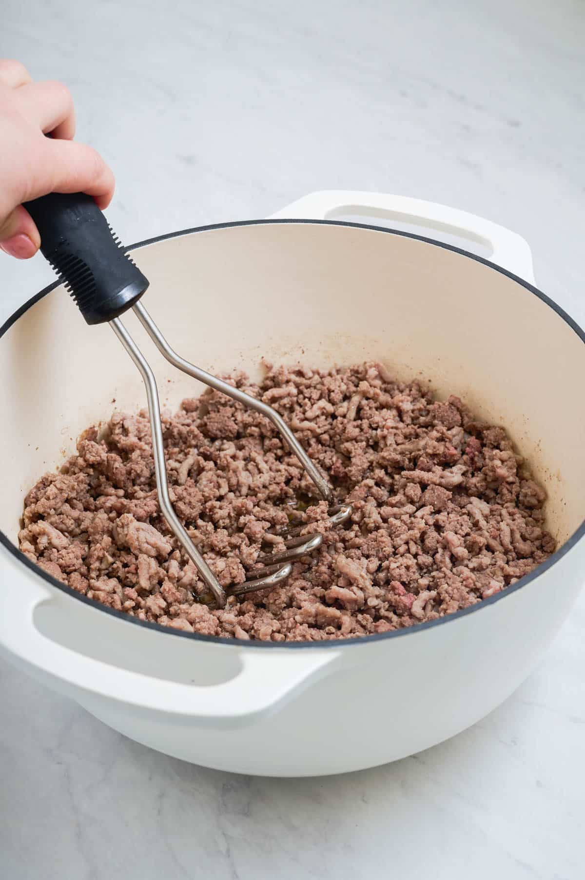 Ground beef is cooked in a Dutch oven until browned.