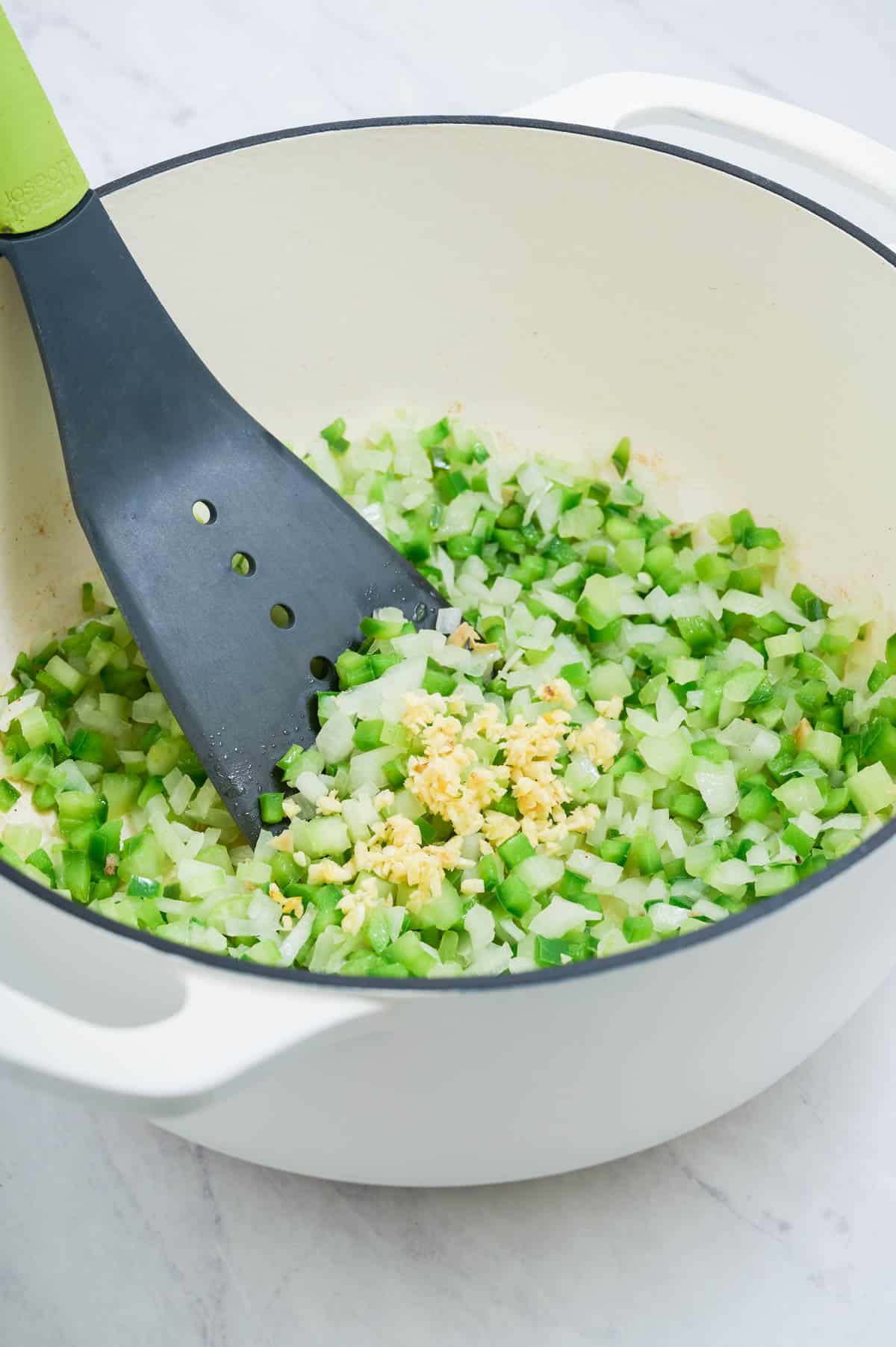 Garlic is added to the onion, celery, and bell pepper.