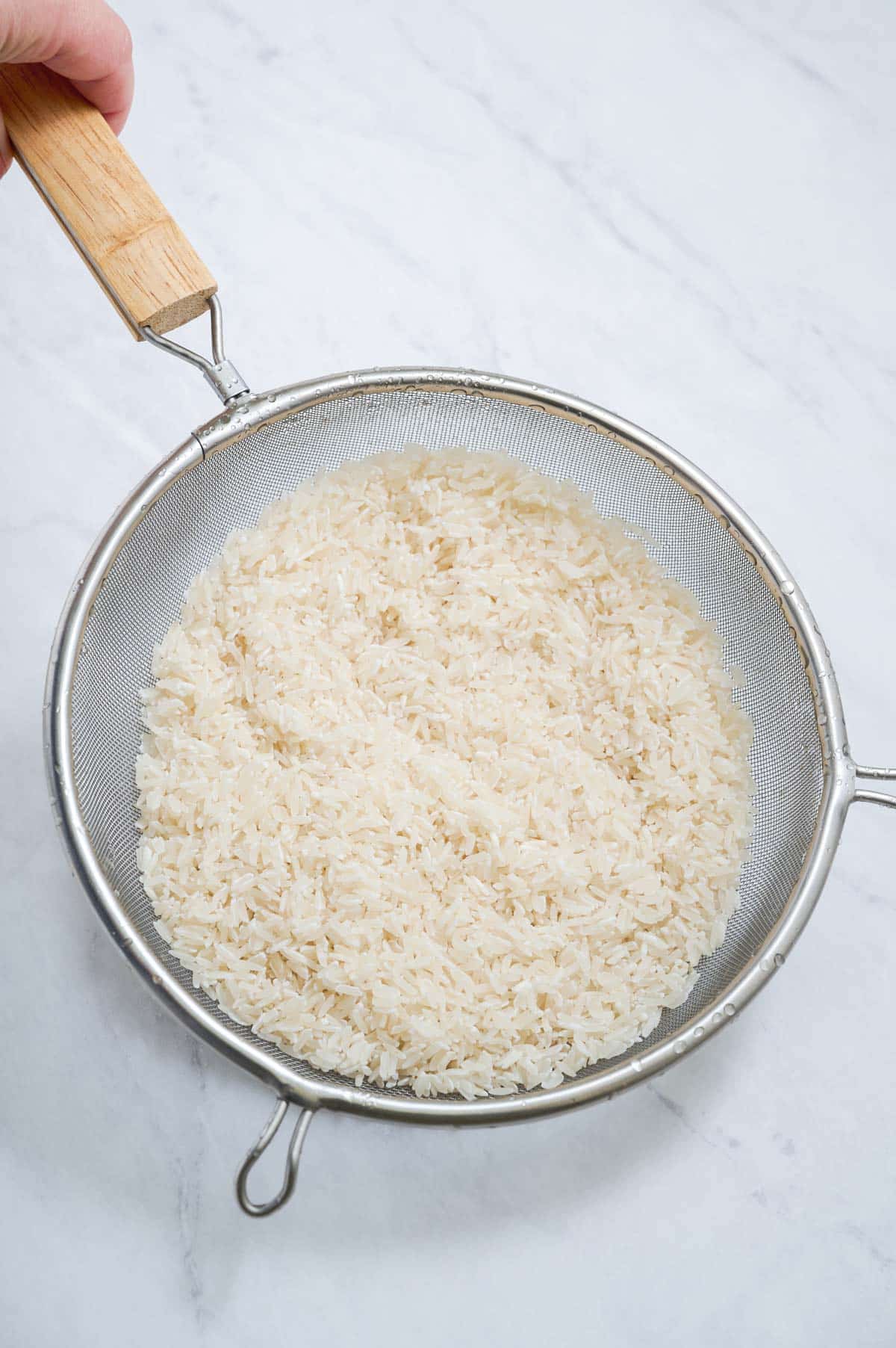 Rice is rinsed in a strainer.