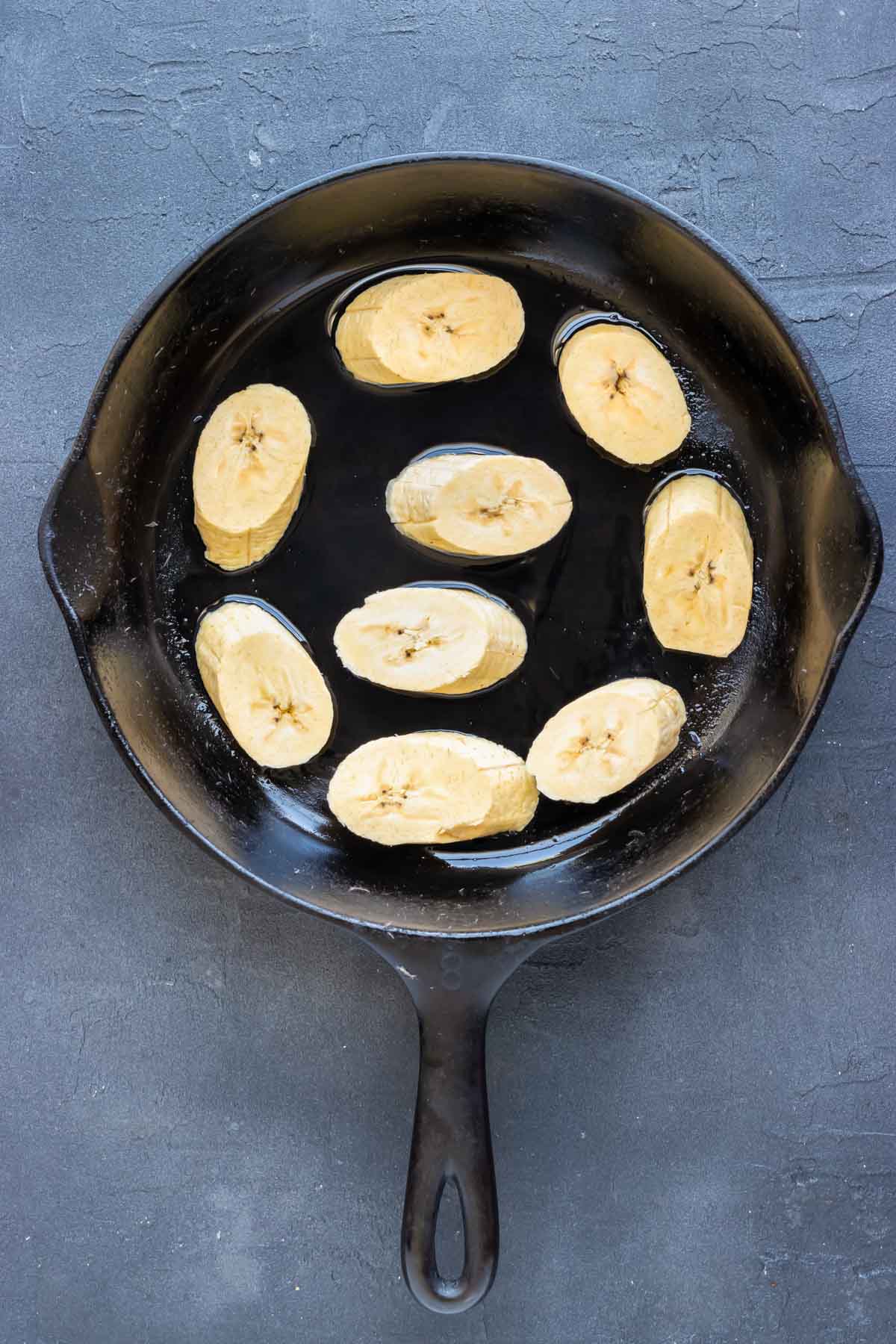 Sliced plantains are added to the melted oil.
