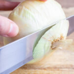 The end of an onion is sliced off.