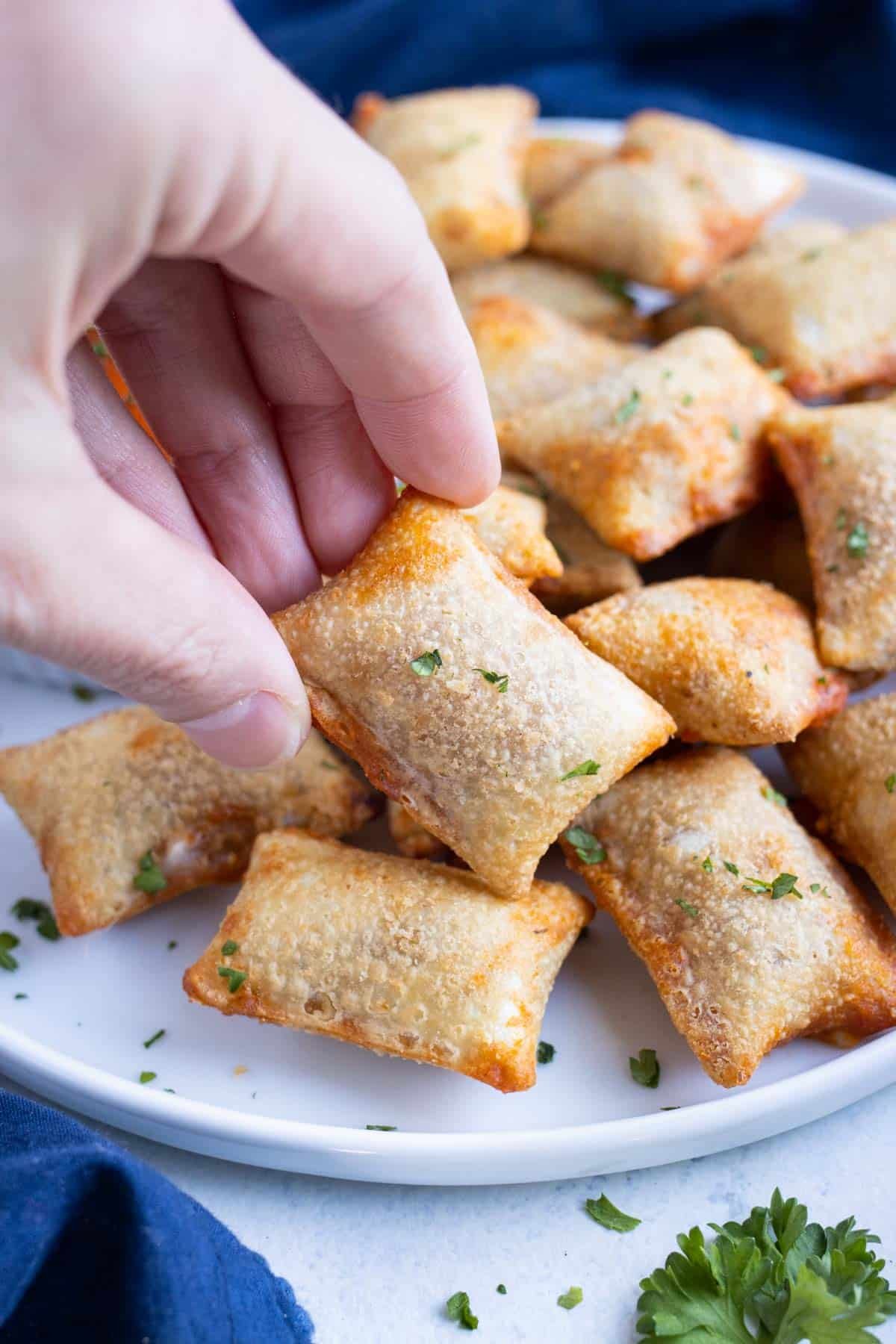 A hand picks up a pizza roll cooked in the air fryer.