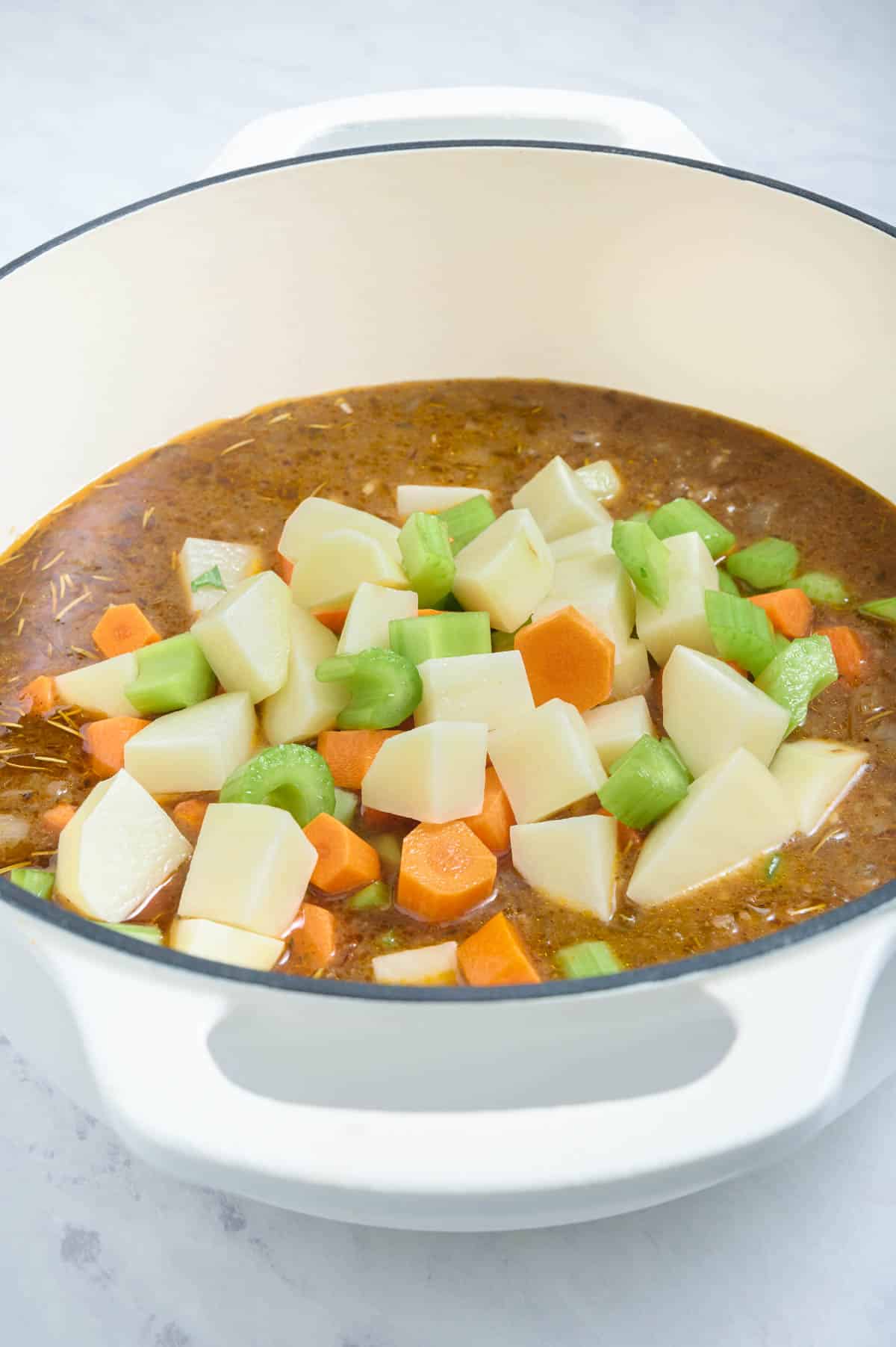 Chopped veggies are added to the stew.