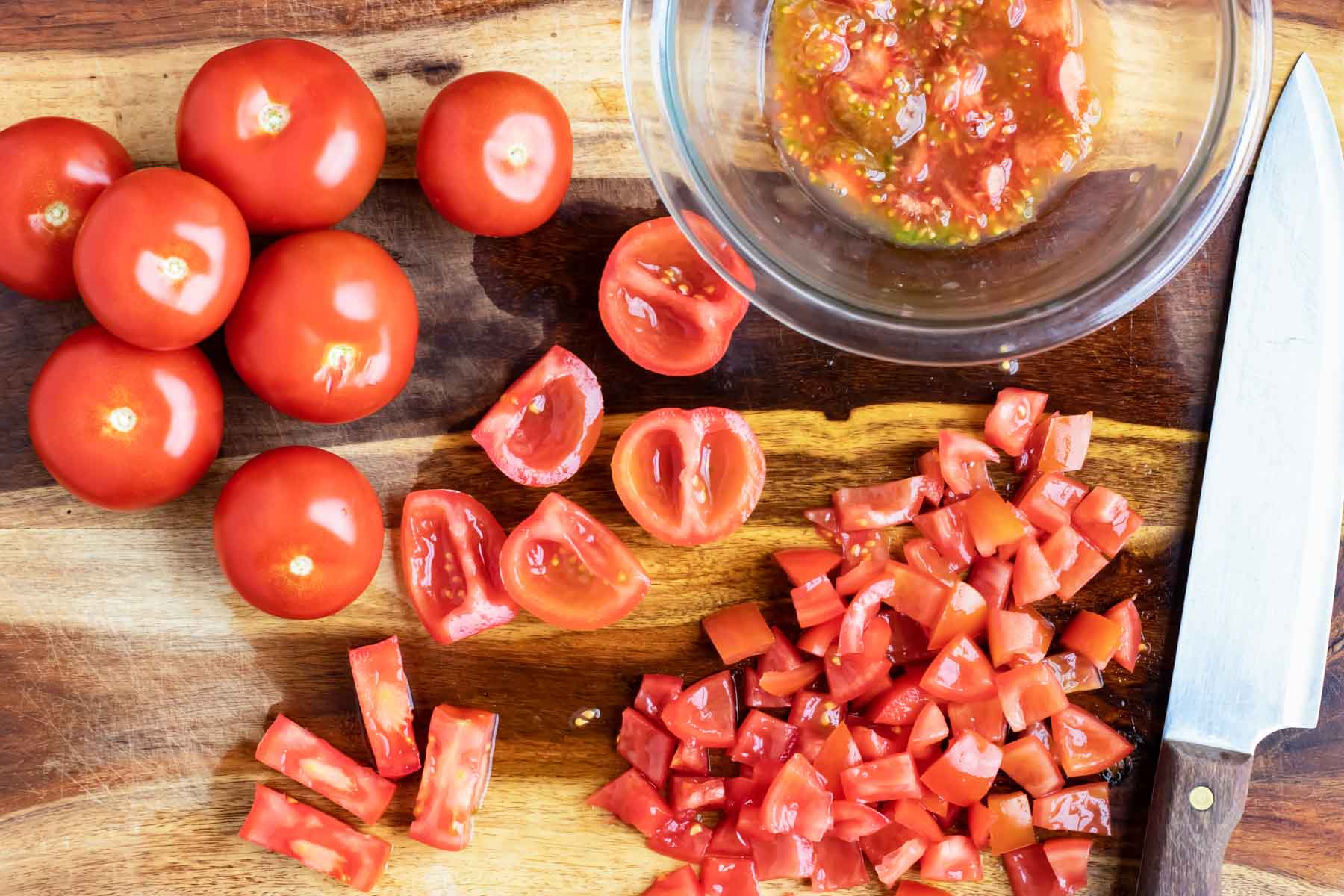 Finely diced tomatoes on a wooden cutting board for a homemade pomodoro sauce recipe.