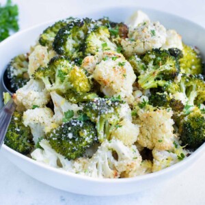 Serve roasted broccoli cauliflower in a bowl topped with fresh parsley for a keto side dish.