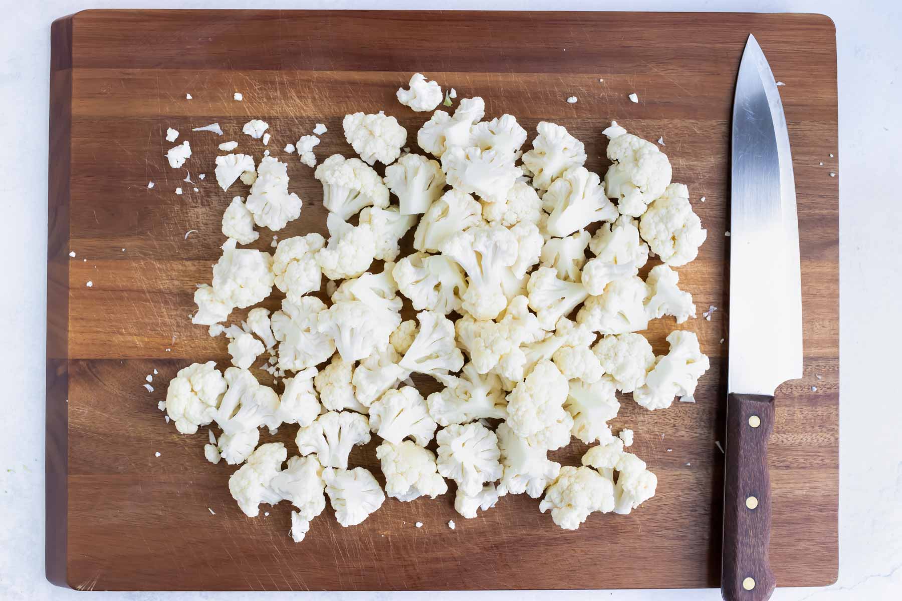 Fresh cauliflower is cut into florets before roasting in the oven.