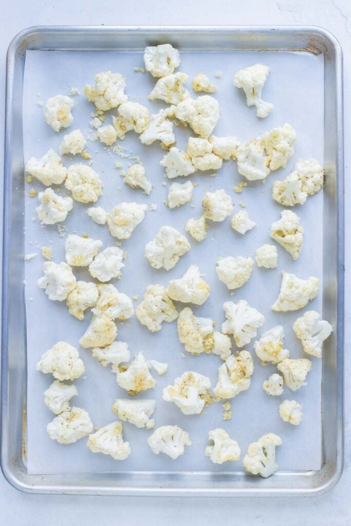 Seasoned cauliflower spread in a single layer on a sheet pan to roast first.