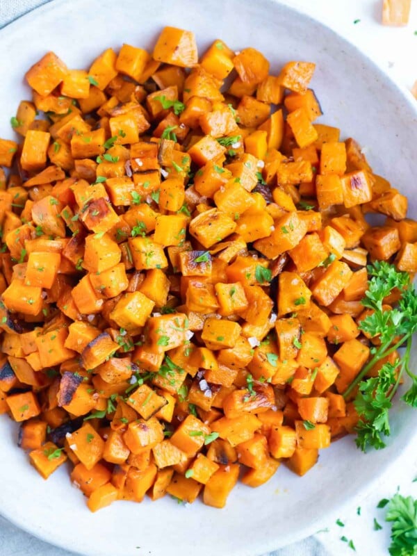 Roasted sweet potato cubes are served in a white bowl after baking in the oven.